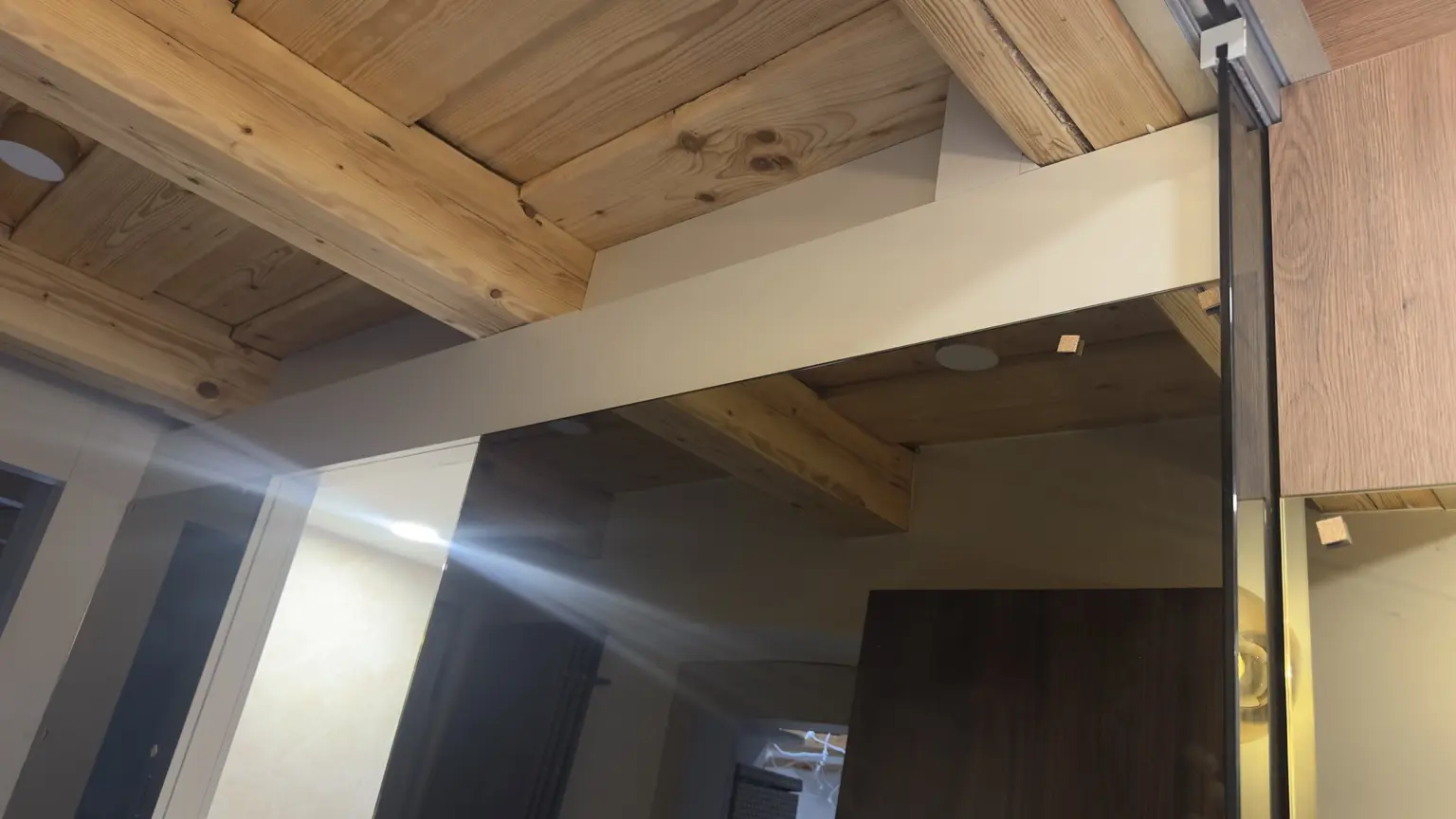 Detail bronzového zrcadla v dřevěném interiéru